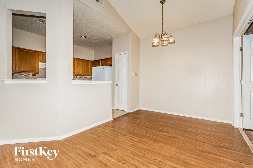 A spacious room with wooden floors and a chandelier hanging from the ceiling.