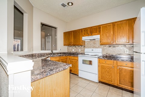 A kitchen with wooden cabinets and a marble countertop.