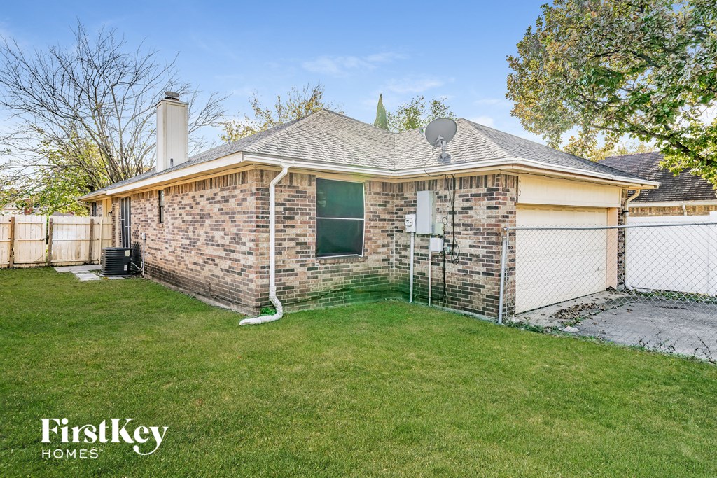 A brick house with a white garage door and a satellite dish on the roof.
