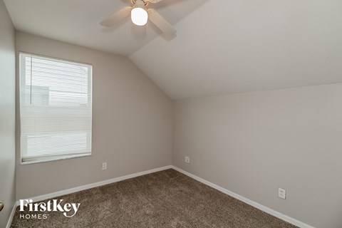 the bedroom has a ceiling fan and a carpet