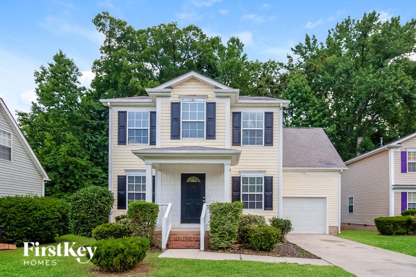 a white house with black window shutters and a sidewalk