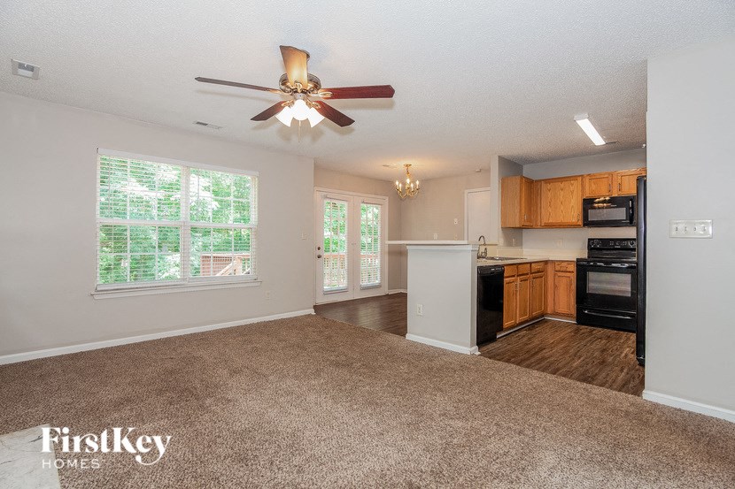 an empty living room and kitchen with a ceiling fan