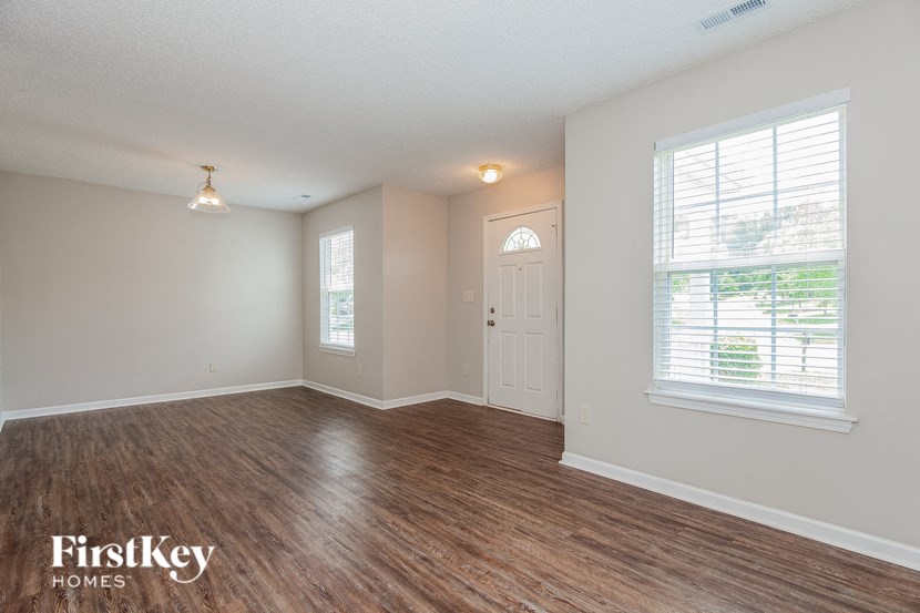 an empty living room with a white door and a window