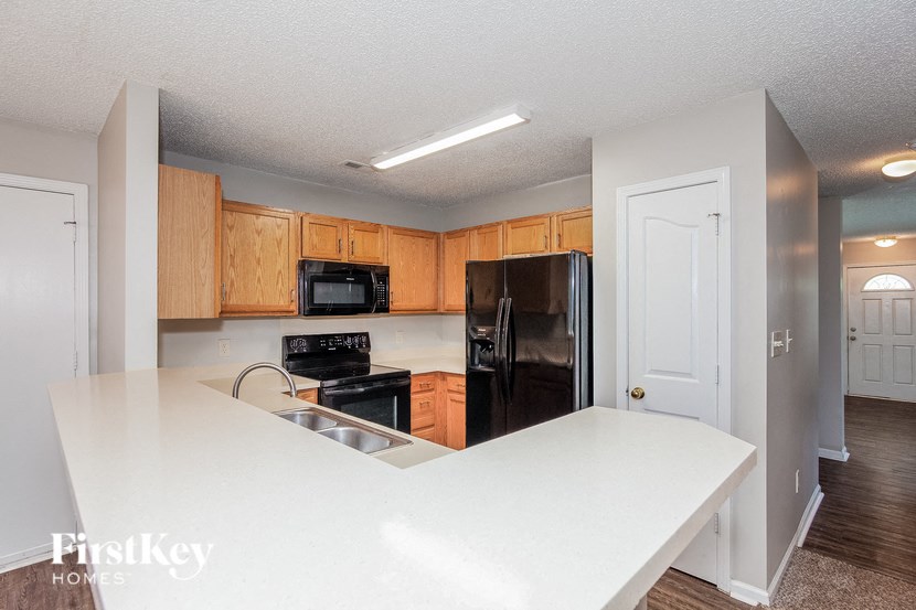 a kitchen with a white counter top and a black refrigerator