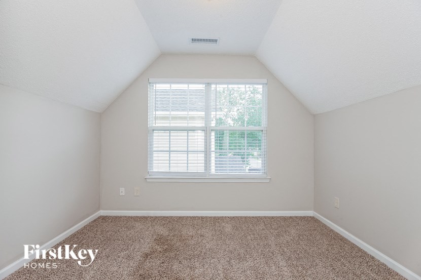 an empty bedroom with a window and carpet