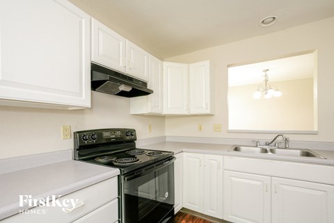 A kitchen with a black stove top oven and white cabinets.