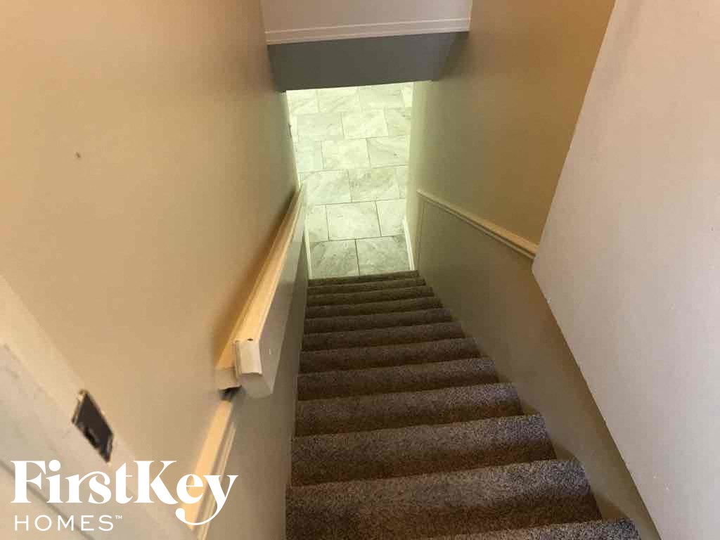 a staircase with carpeted stairs leading up to a hallway with white walls and a