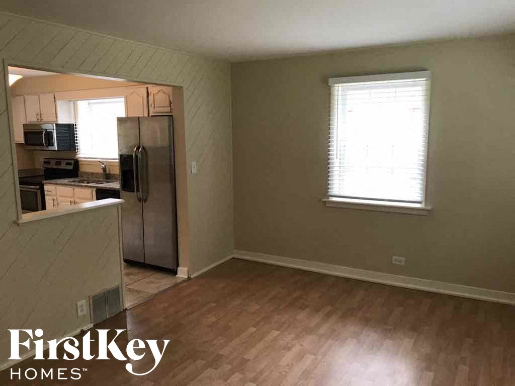 an empty kitchen with a refrigerator and a wood floor