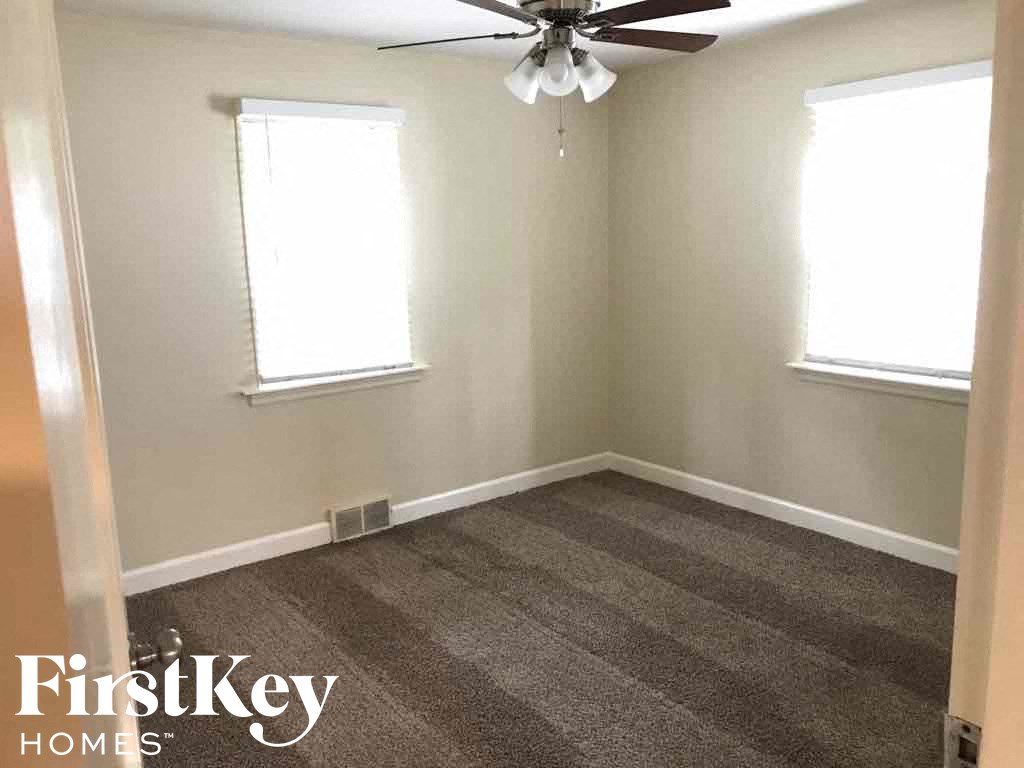 a empty room with a carpeted floor and a ceiling fan
