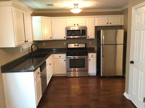 A kitchen with white cabinets and a black countertop.
