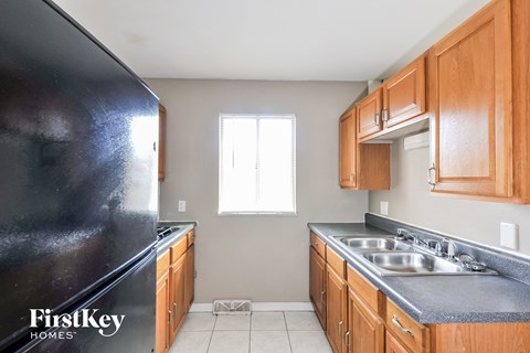 A kitchen with a black refrigerator and wooden cabinets.