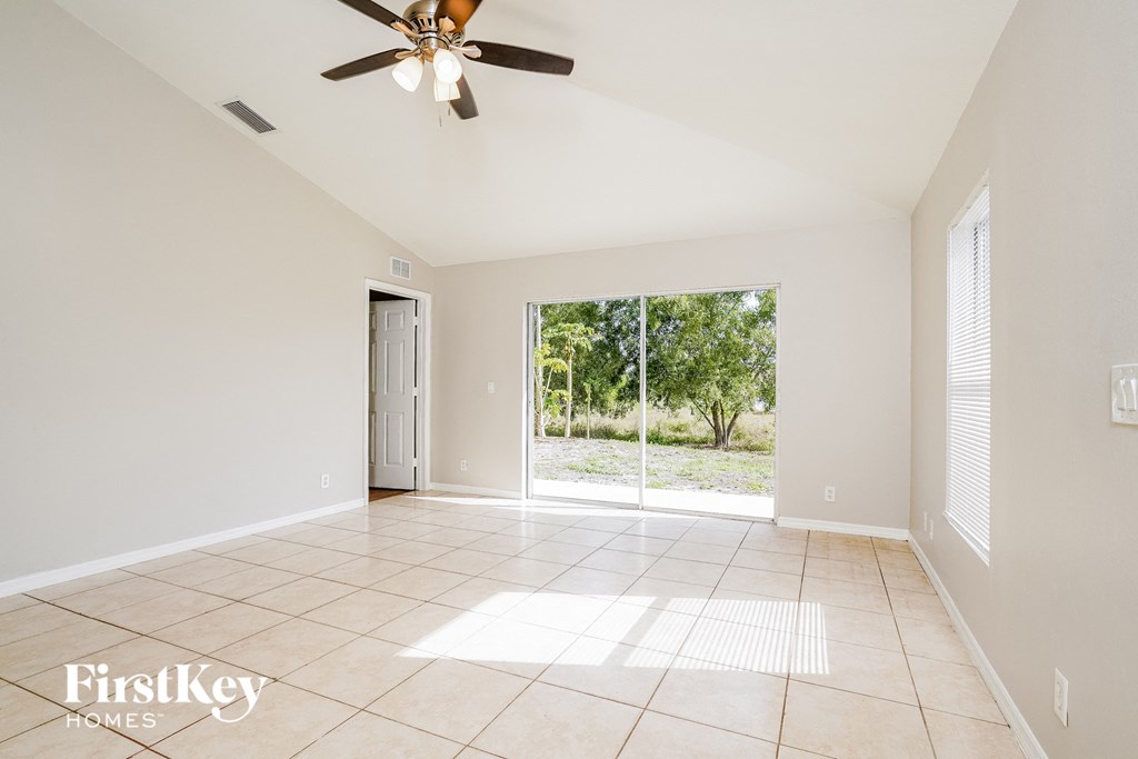 A spacious room with a ceiling fan and sliding glass doors leading to a garden.