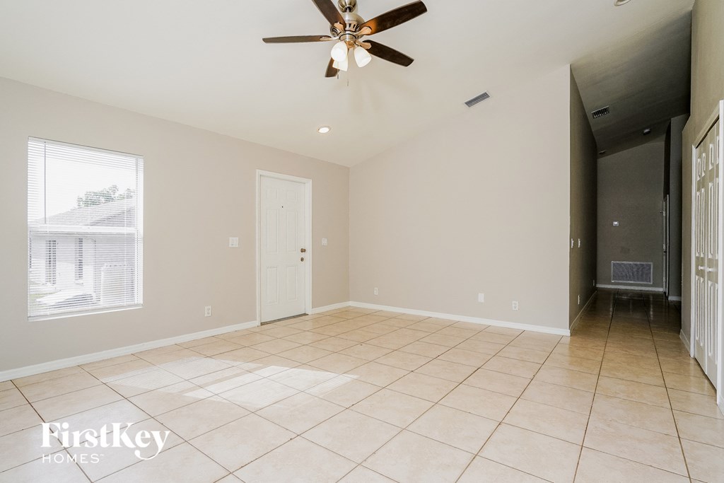 A spacious room with a ceiling fan and a large window.