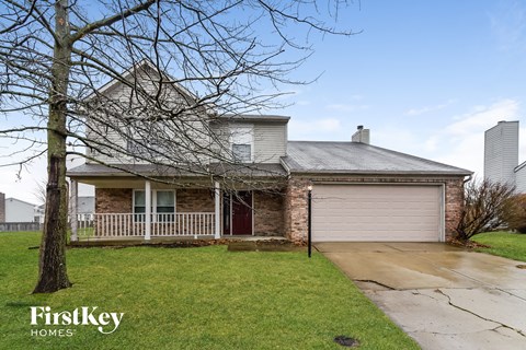 the front of a brick house with a white garage door