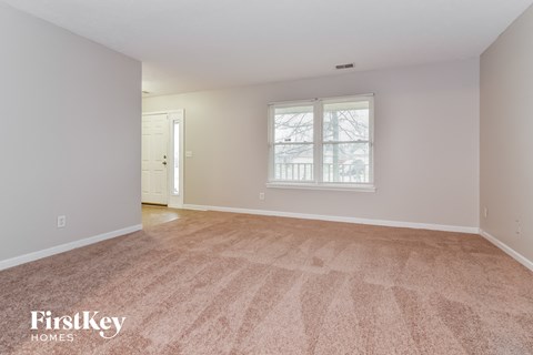 a spacious living room with carpet and a window