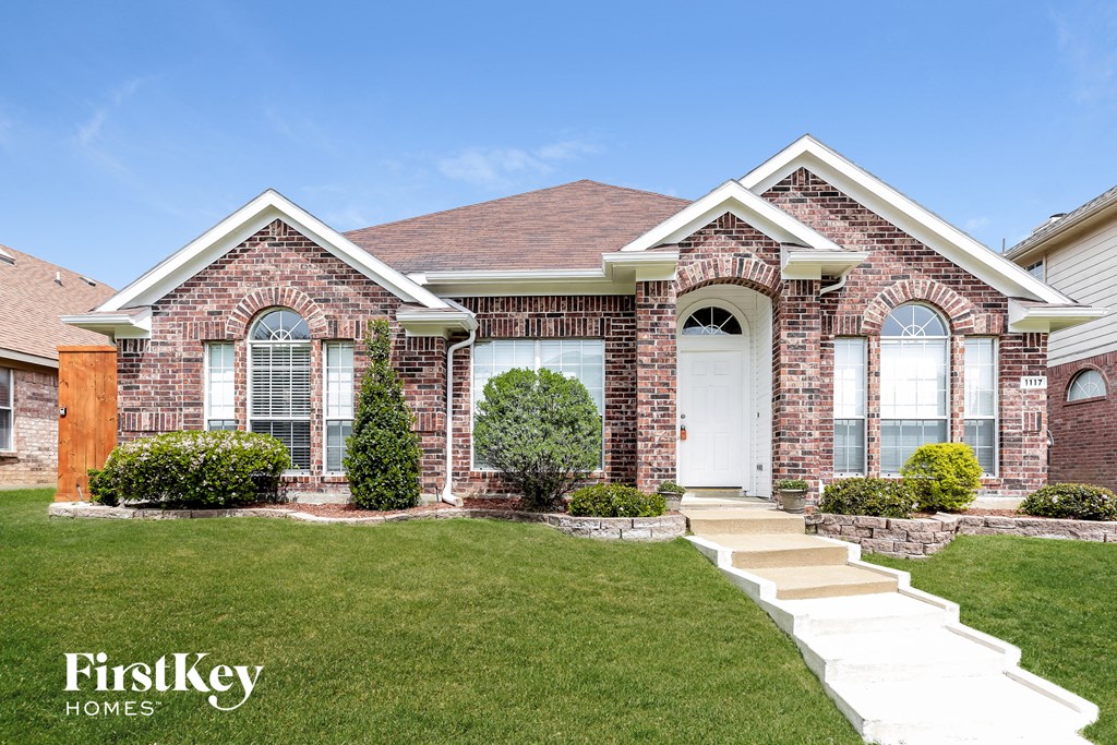 A brick house with a white door and windows is for sale.