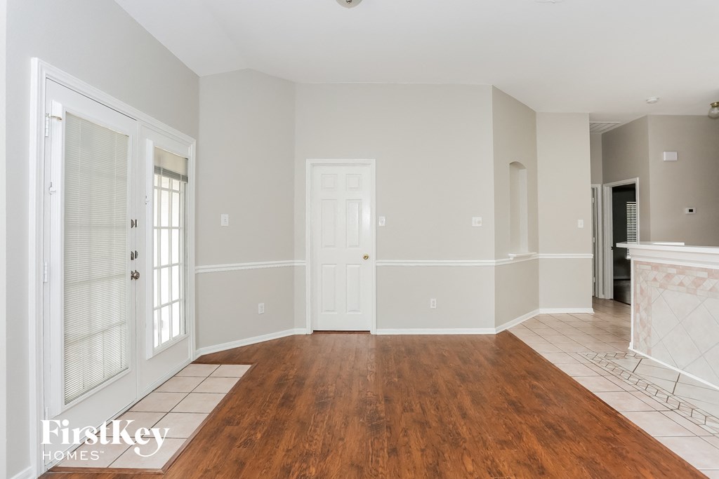 A spacious room with wooden floors and white walls.