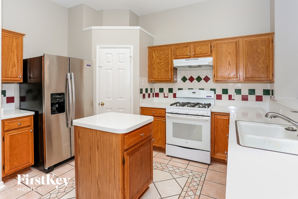 A kitchen with wooden cabinets and a white stove top oven.