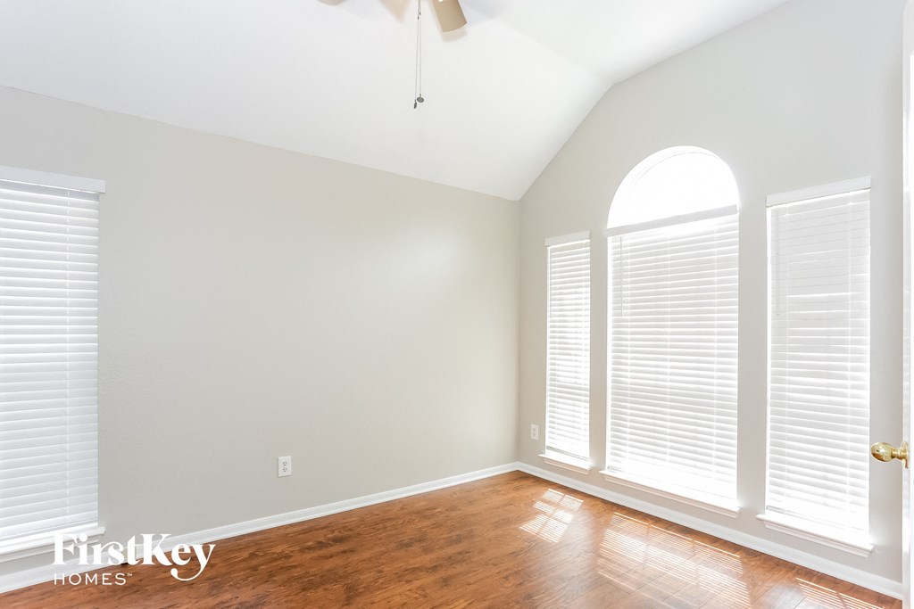 A room with a fan and a window with blinds.