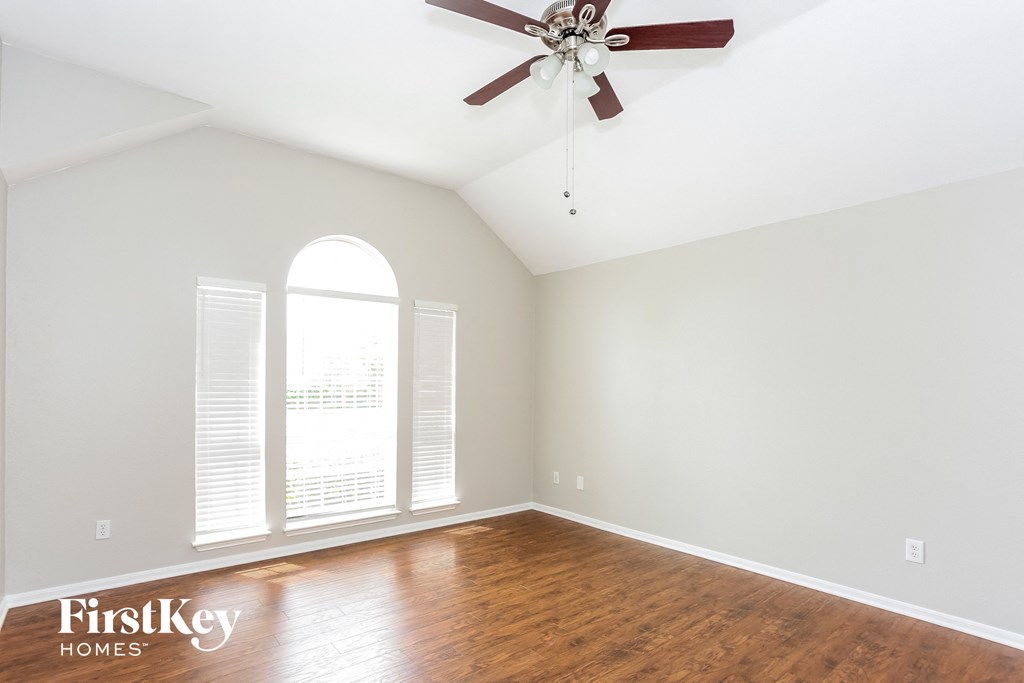 A room with a ceiling fan and wooden flooring.