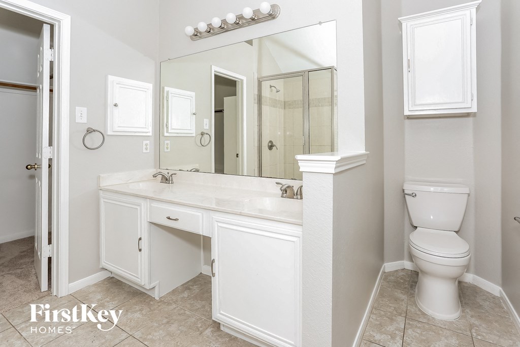 A white bathroom with a mirror, sink, and toilet.