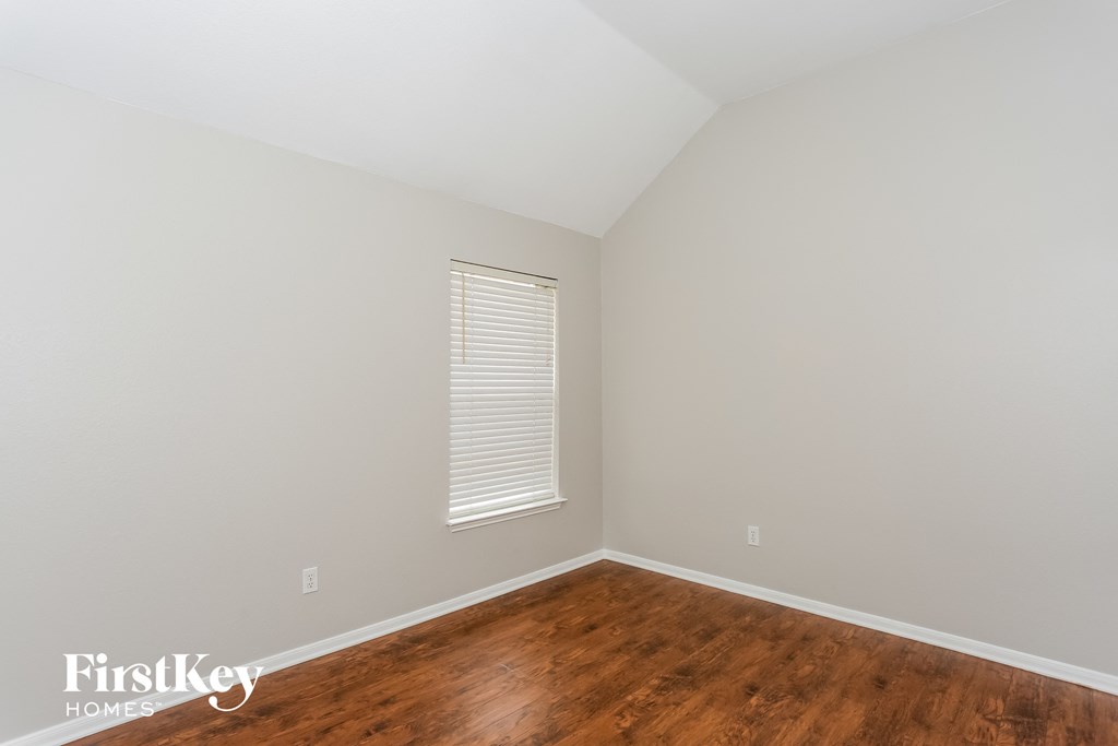 A room with wooden flooring and a window with blinds.
