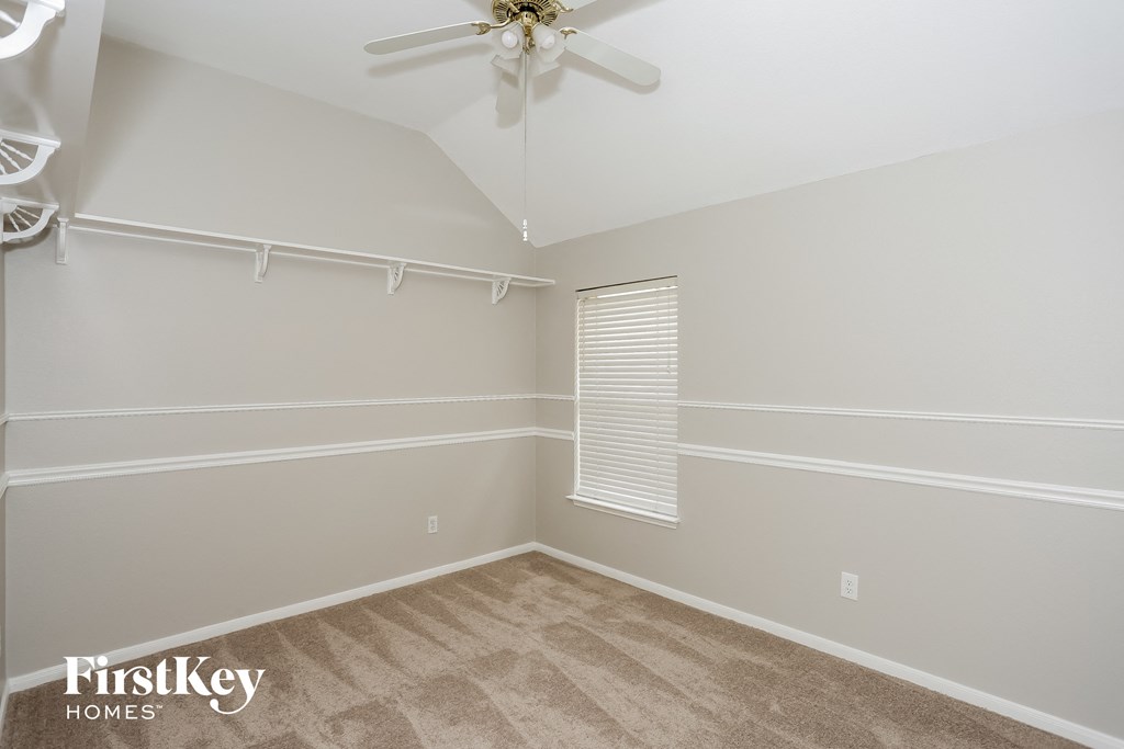 A room with a ceiling fan and a window with blinds.