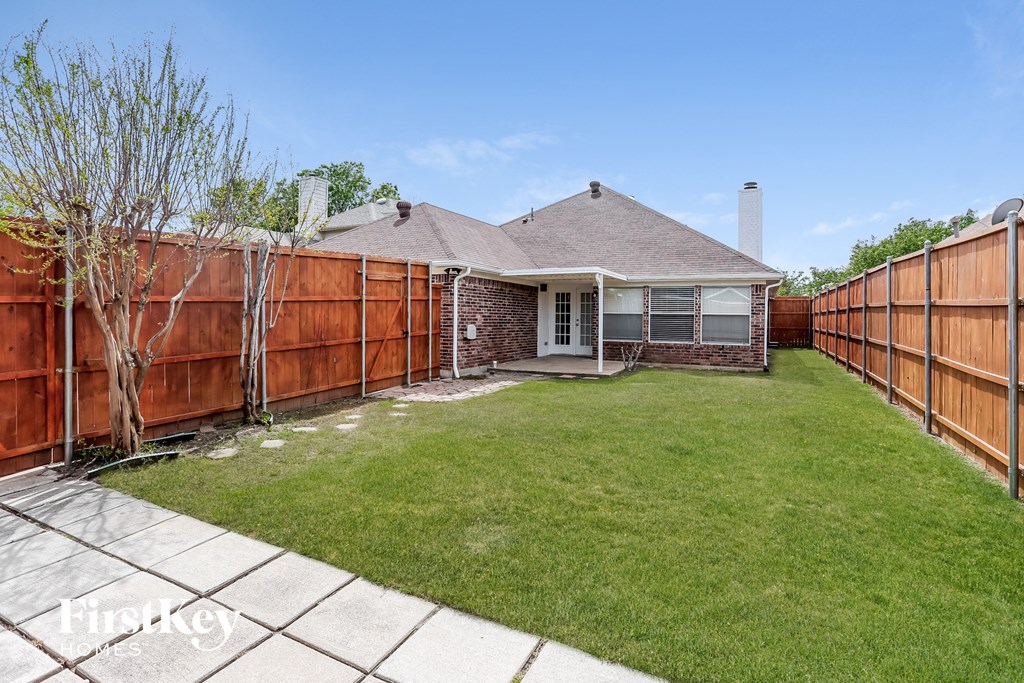 A backyard with a fence and a house.