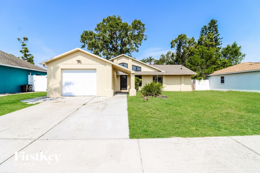 A house with a garage is surrounded by a grassy lawn.