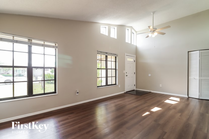 A spacious room with wooden floors and a ceiling fan.