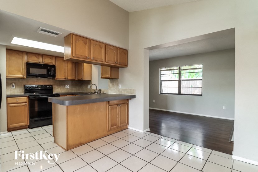 A kitchen with wooden cabinets and a tiled floor.