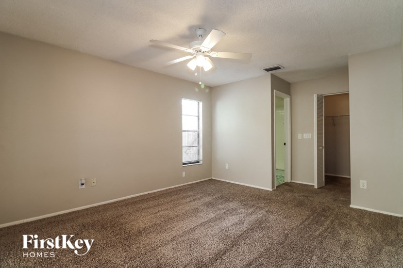 A room with a carpeted floor and a ceiling fan.