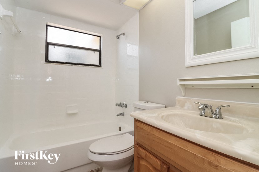A white bathroom with a wooden vanity and a toilet.