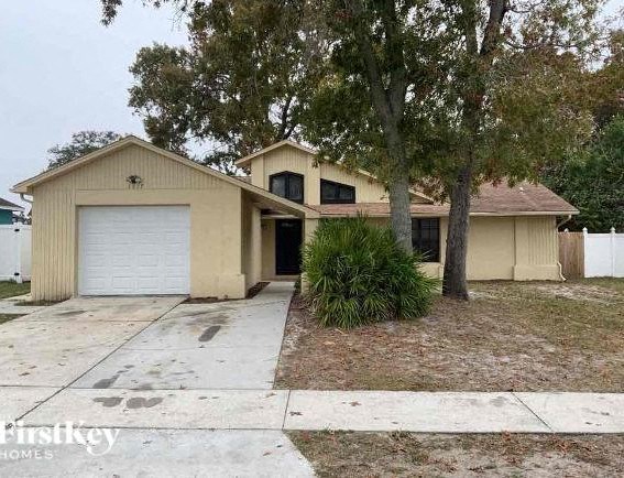 A two-story house with a garage and a tree in front.