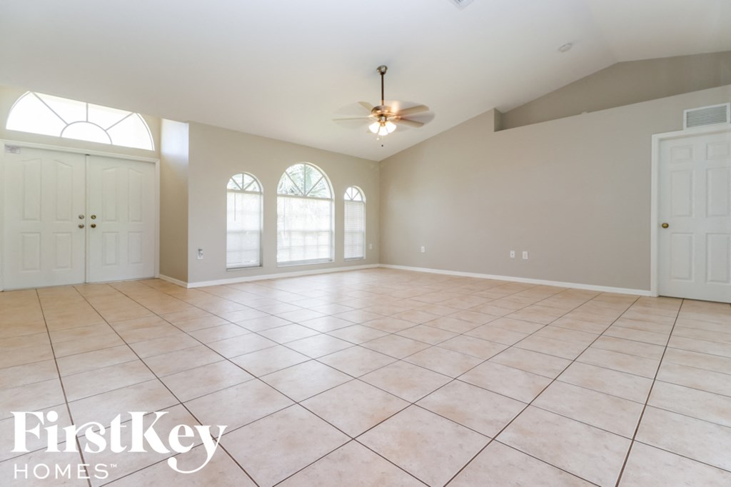 an empty living room with tile floors and a ceiling fan