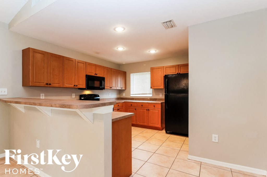 a kitchen with wooden cabinets and a black refrigerator