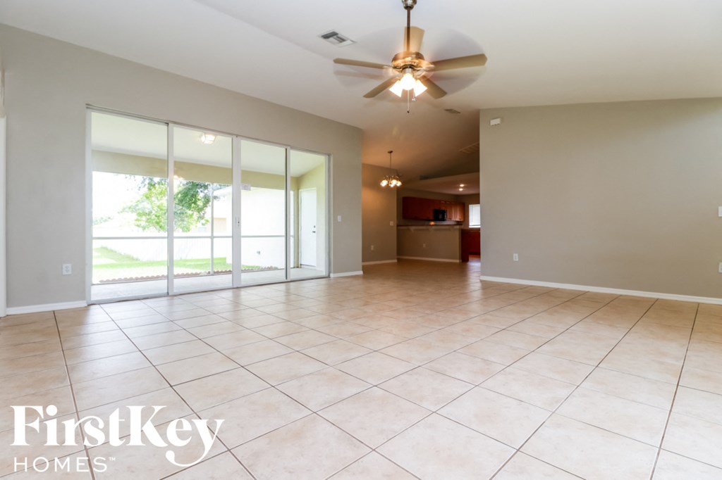 an empty living room with a ceiling fan and tiled floors
