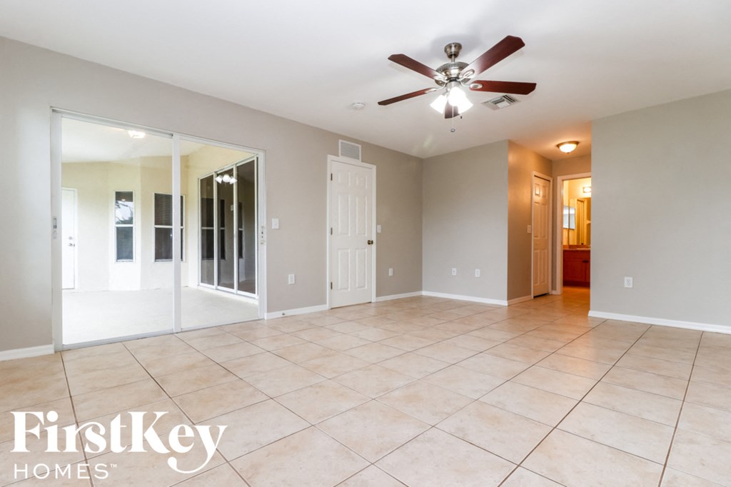 an empty living room with a ceiling fan and a tile floor