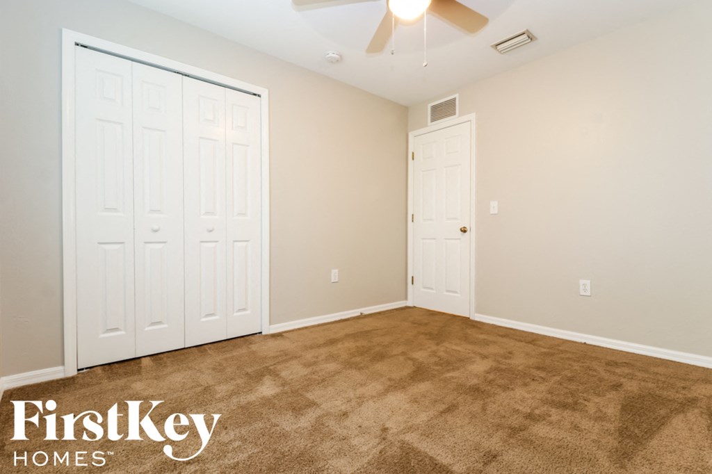 a room with carpet and two closets and a ceiling fan