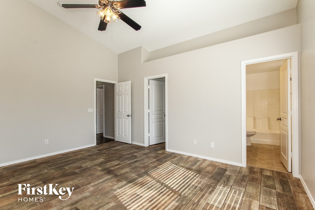 a living room with a ceiling fan and a door to a bathroom