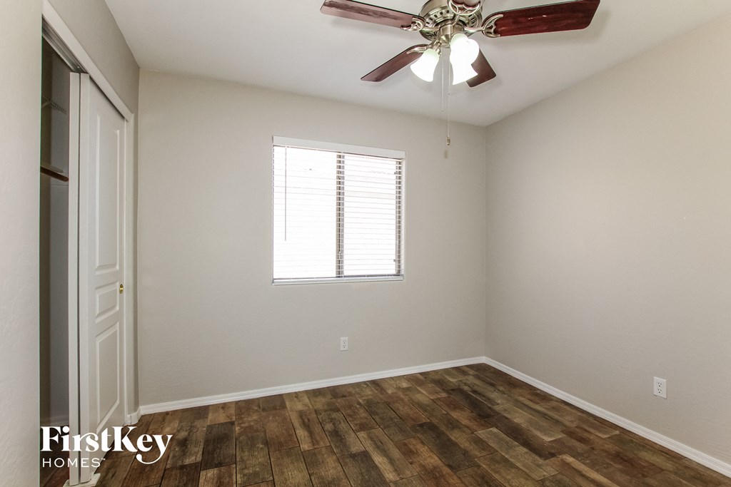 a bedroom with wood flooring and a ceiling fan