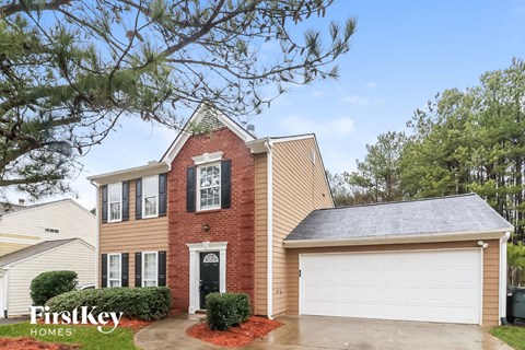 A house with a red brick facade and a white garage door is for sale.