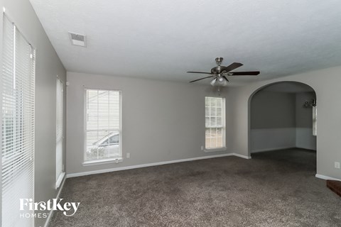 A spacious room with a ceiling fan and two windows.