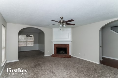 A living room with a fireplace and a ceiling fan.