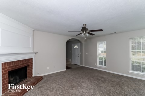 A spacious room with a fireplace and a ceiling fan.