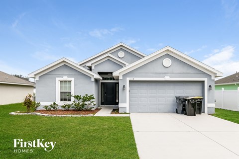 a white and blue house with a driveway and grass