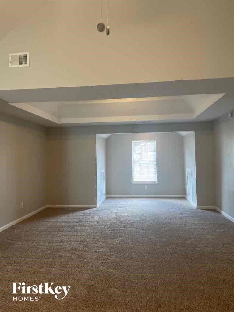 an empty living room with white carpet and a window