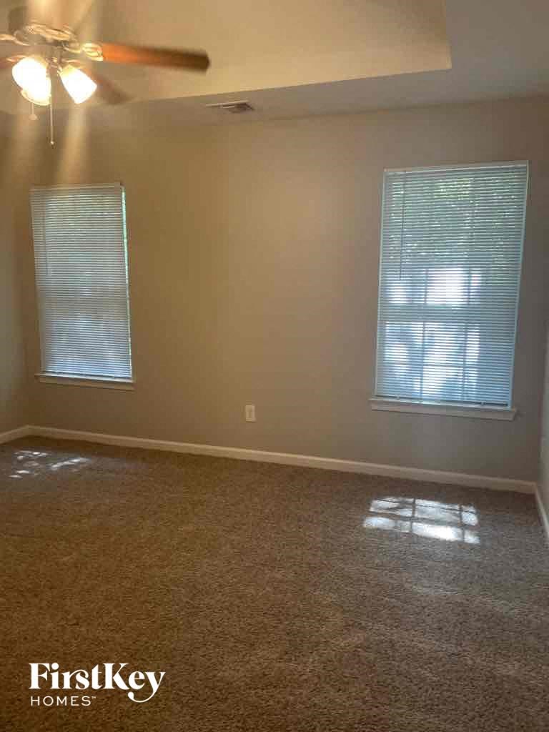 an empty living room with a ceiling fan and two windows