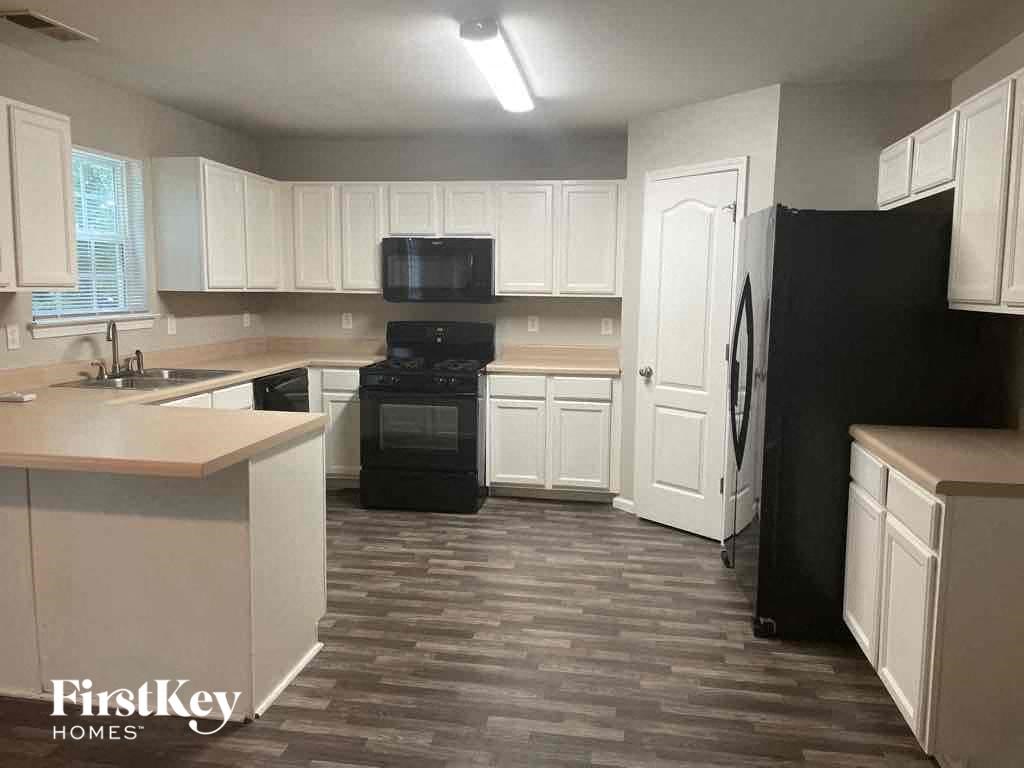 an empty kitchen with white cabinets and black appliances