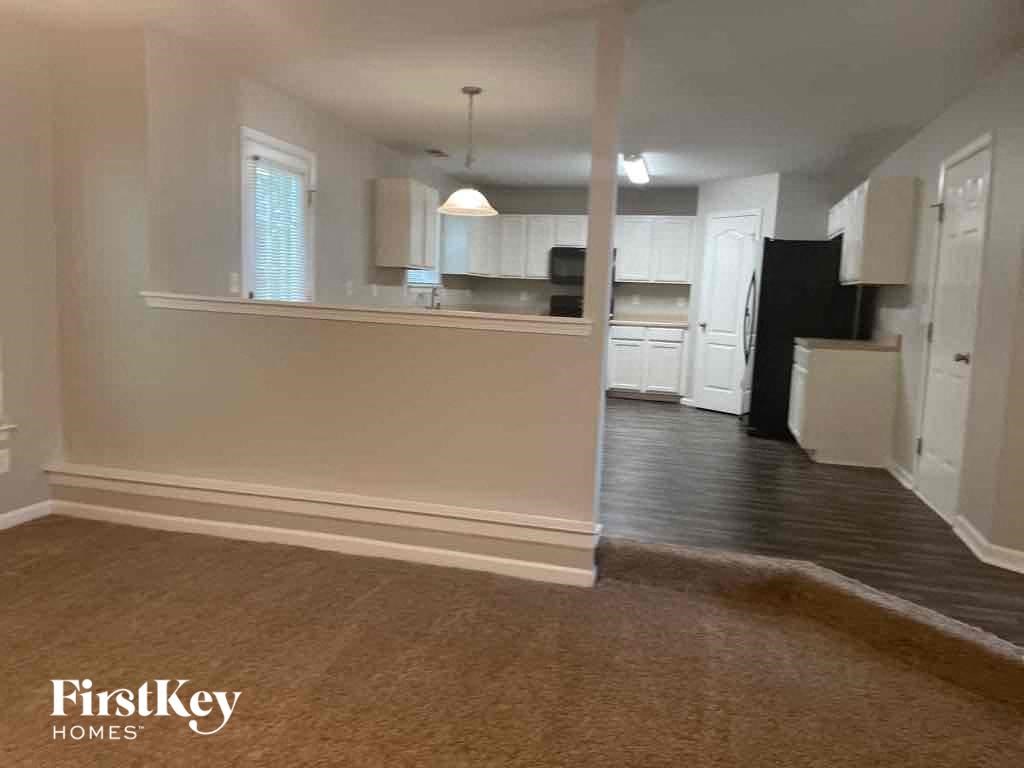 an empty living room and kitchen with a hard wood floor